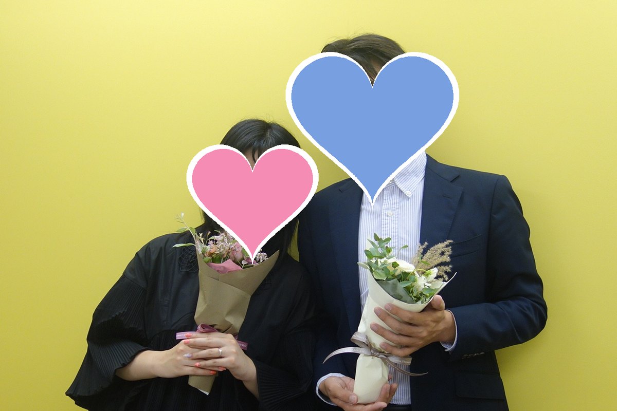 成婚のお祝いの日に、花束を持ったS・Mさんとお相手(お二人のお顔はハートで隠しています)