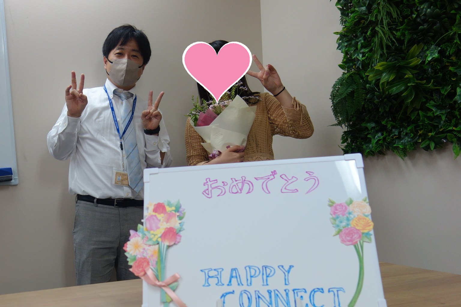 おめでとう会で花束を持ったE・Mさんと、成婚カウンセラーの石井（E・Mさんのお顔はハートで隠しています）